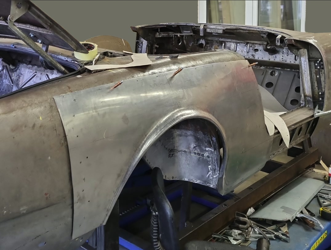 Carrosserie met nieuw plaatwerk vastgezet met klemmen, op de tillift in de werkplaats